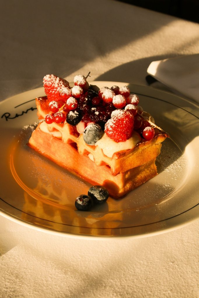 Vaffel med friske bær, creme og flormelis serveret på Ravage.